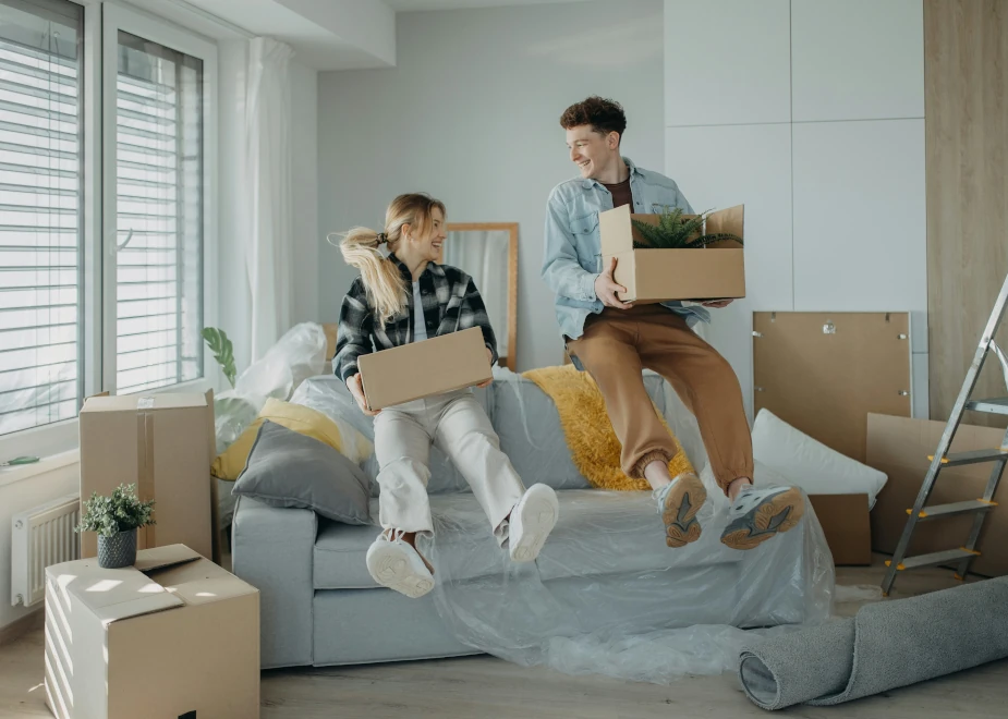 Ein Paar springt beim Umzug zufrieden auf das Sofa